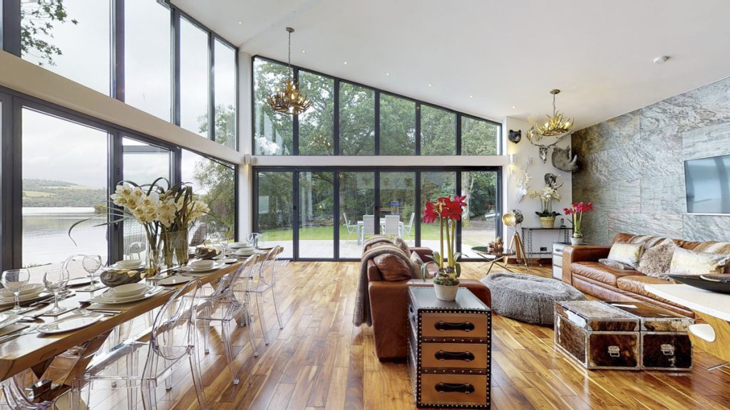 Cameron North Lodge dining table set for dinner with glass wall and sofas