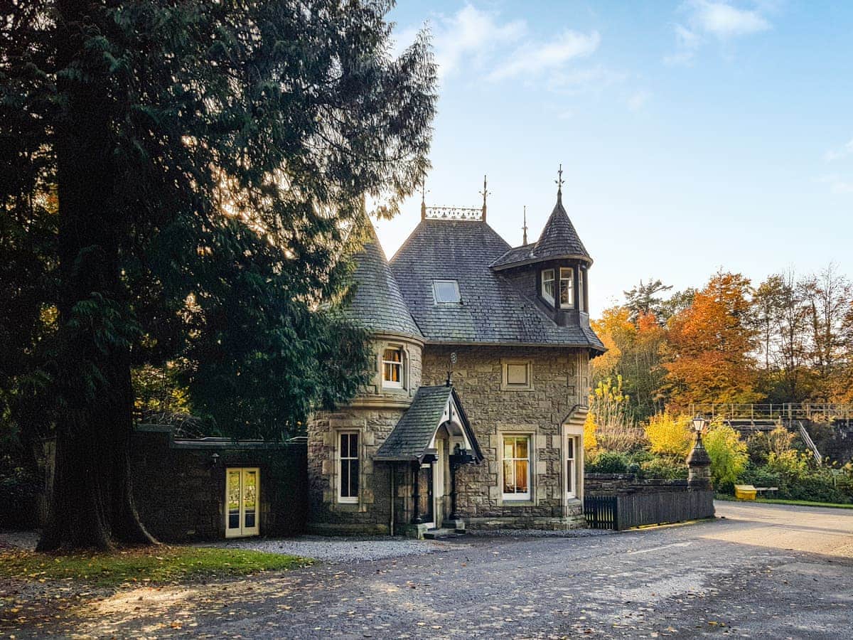 Traditional Scottish gatehouse lodge with turrets surrounded by trees