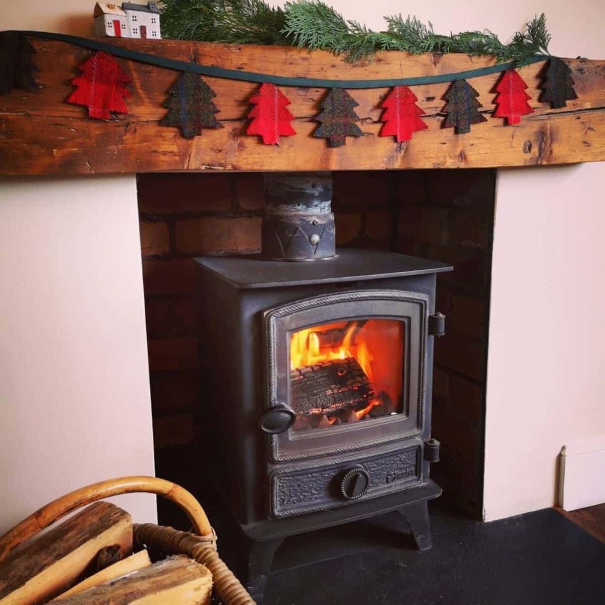 Harris tweed xmas tree bunting hung on a wooden mantelpiece over a woodburning stove